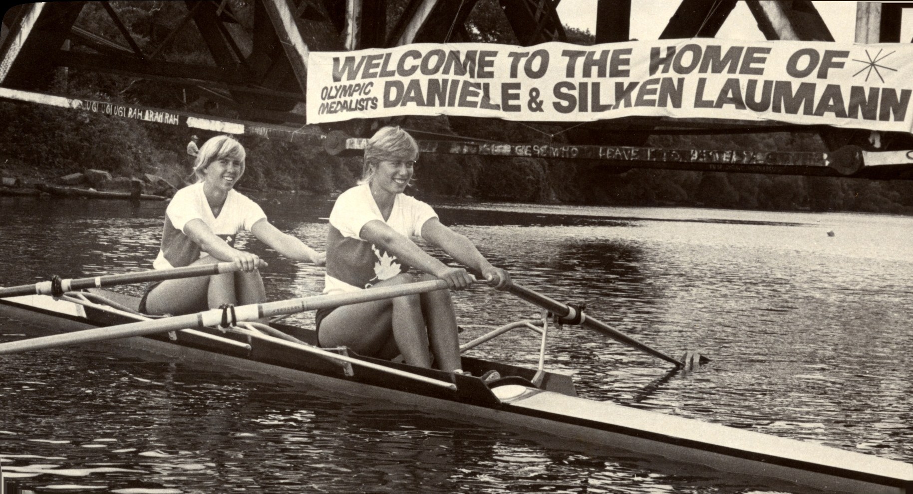 Silken and Daniele Laumann rowing beneath a banner reading Welcome to the home of Olympic medalists